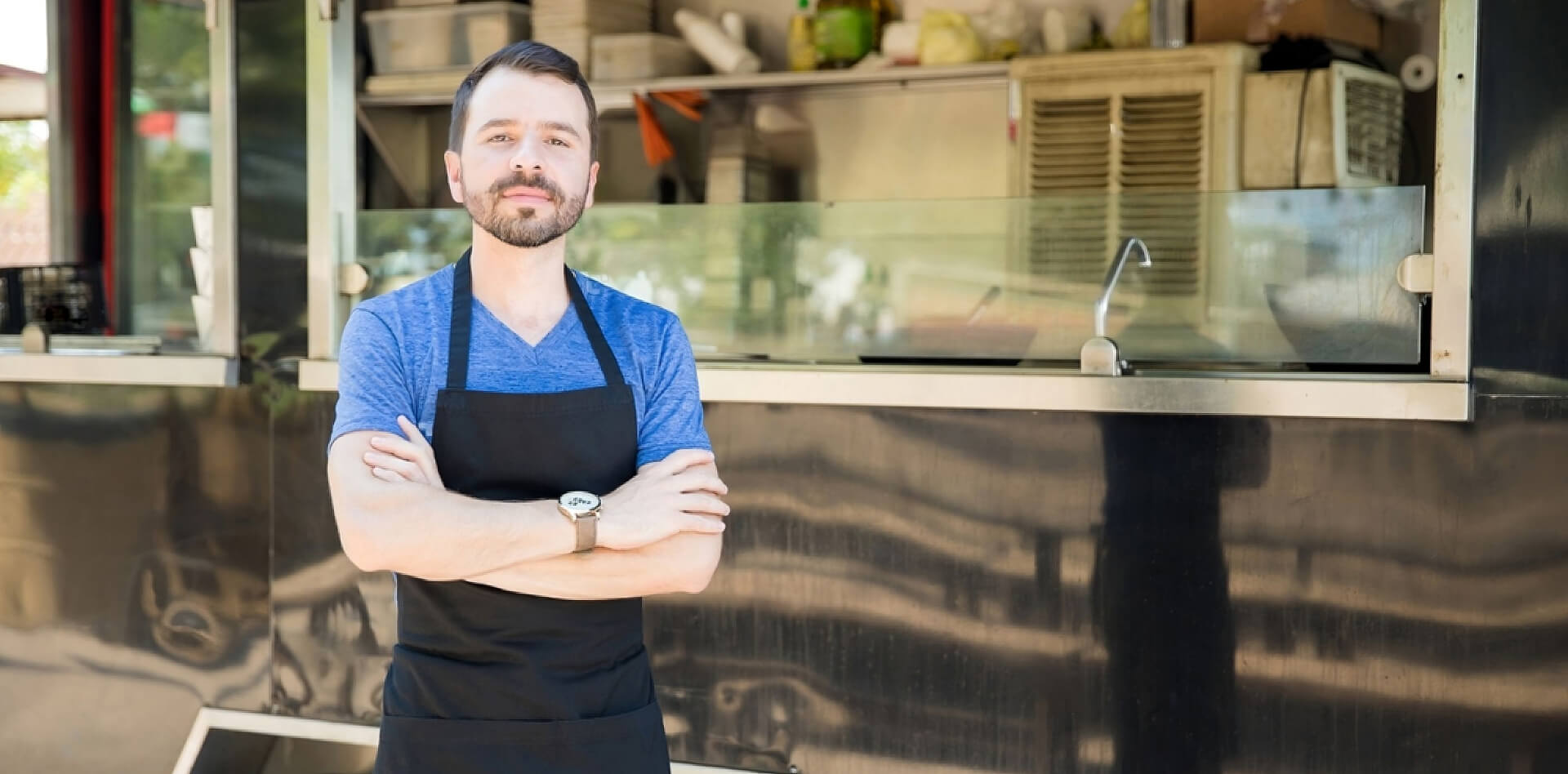 stock-photo-portrait-of-a-handsome-young-man-with-an-apron-standing-in-front-of-his-food-truck-750252778-transformed-transformed-1